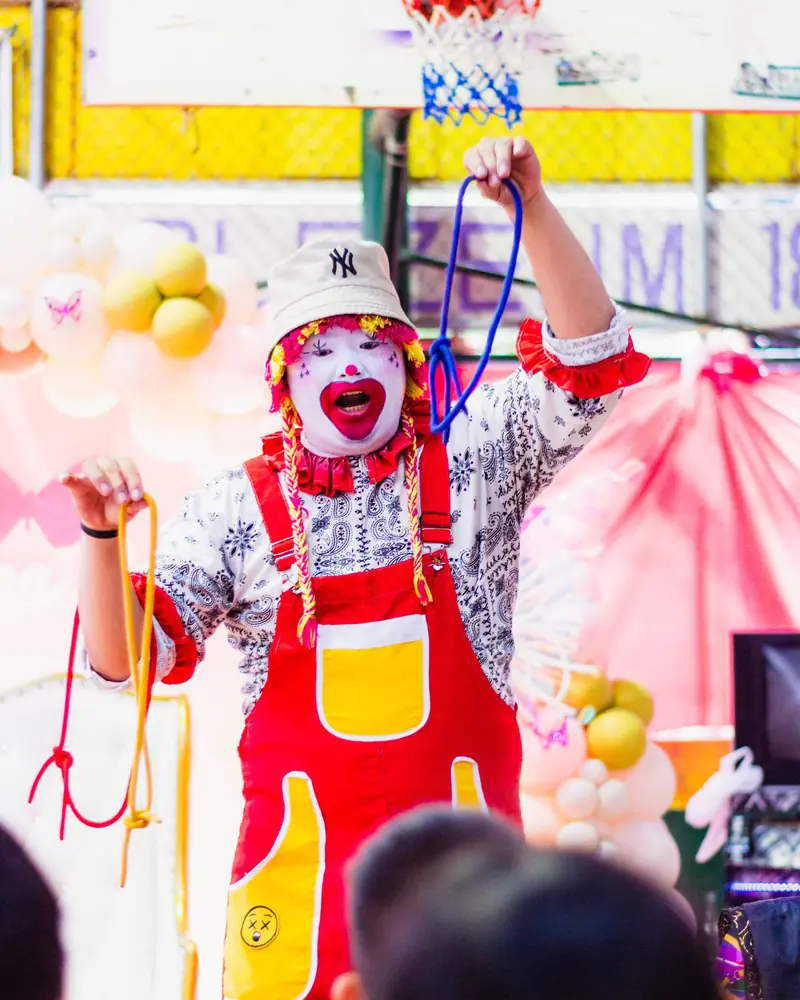 Animatore vestito da clown che gioca con i palloncini a una festa