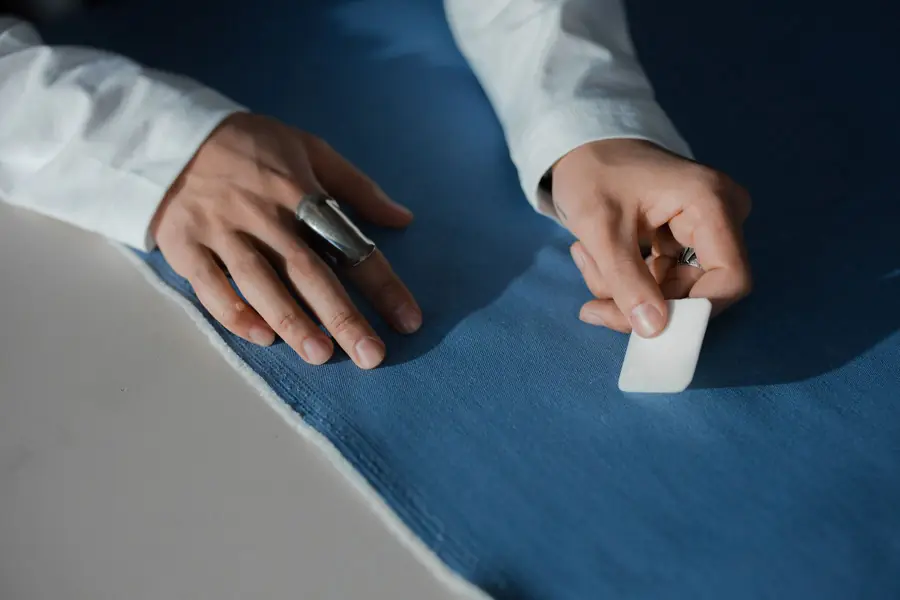 Mani che segnano il tessuto con il gesso da sarto