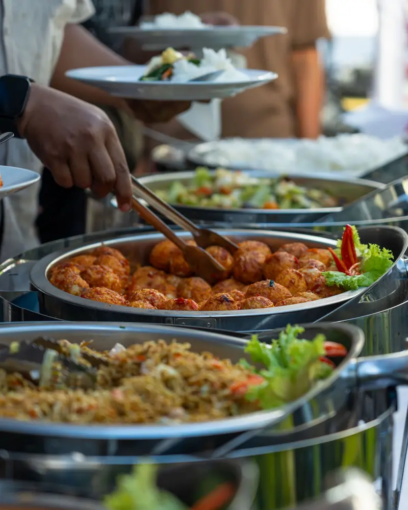Buffet di un evento: i piatti serviti con le pinze dai vassoi caldi