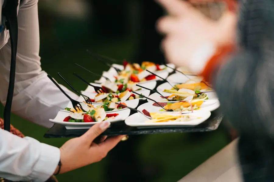Cameriere che porta un vassoio di antipasti fra gli invitati