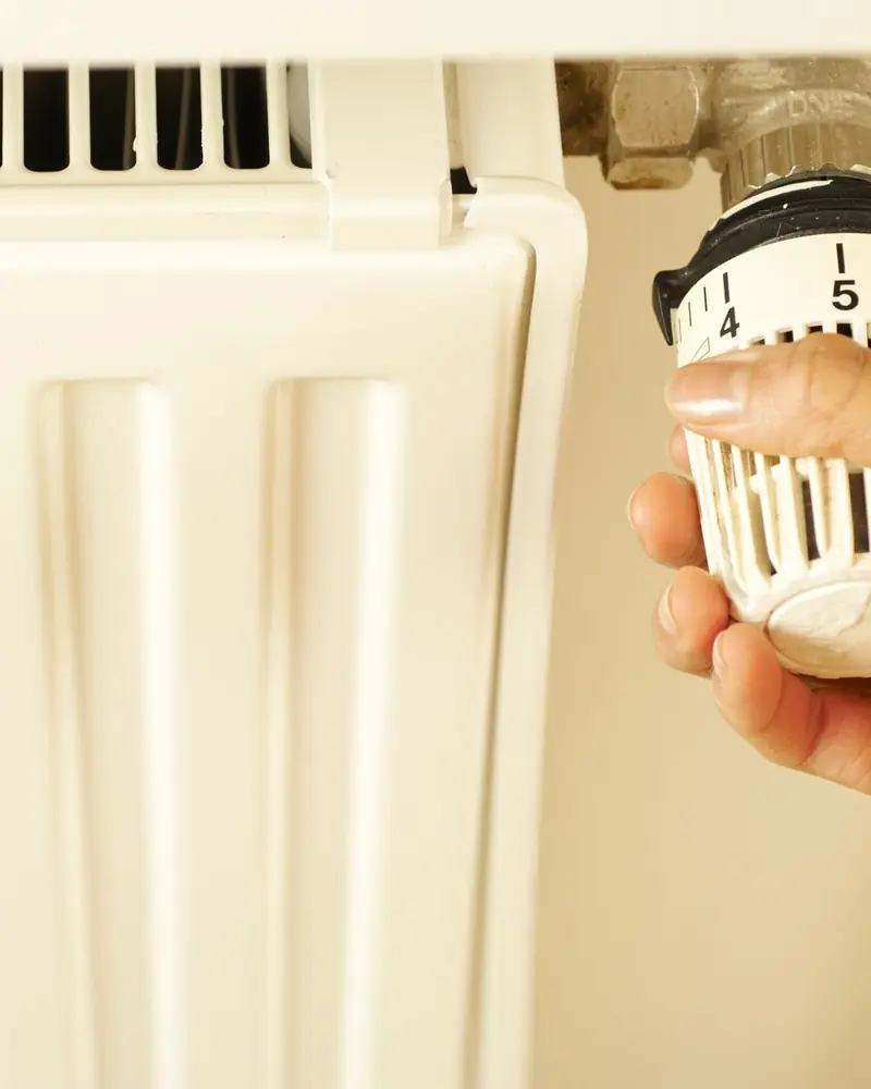 Mano che regola la valvola termostatica di un termosifone