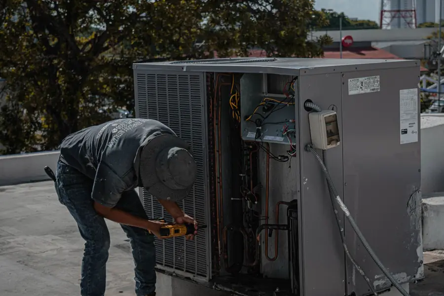 Tecnico al lavoro sull'unità esterna di un condizionatore