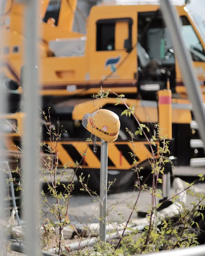 Casco giallo appeso a un palo in un cantiere con la gru