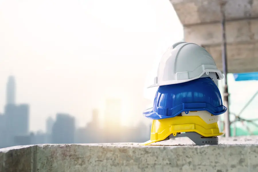 Caschi da cantiere impilati, sullo sfondo la città