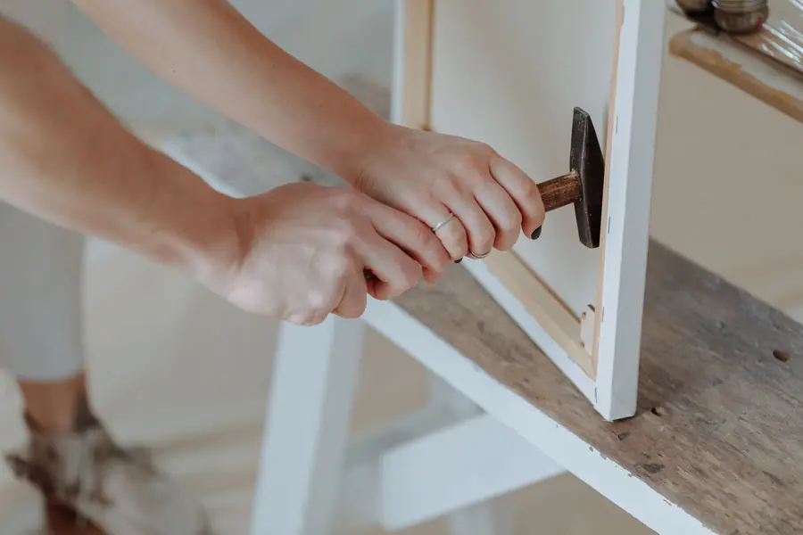 Mani che montano una cornice con il martello