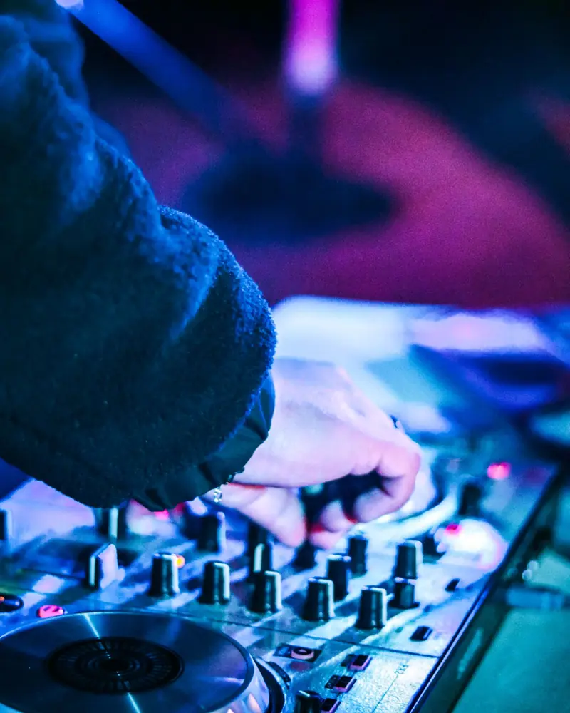 Le mani del dj sulla consolle, fra luci blu e viola