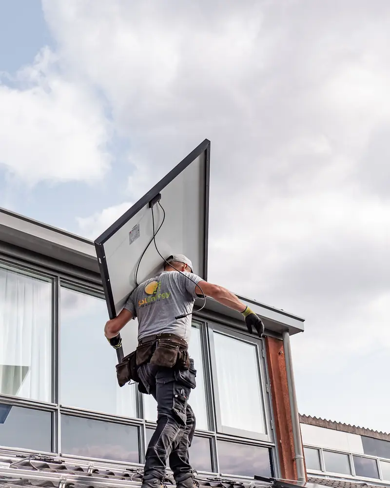 Installatore che porta un pannello solare sul tetto