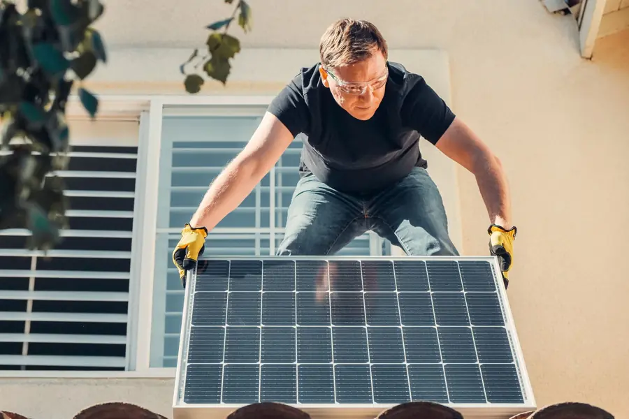 Tecnico che monta un pannello fotovoltaico sul tetto di una casa