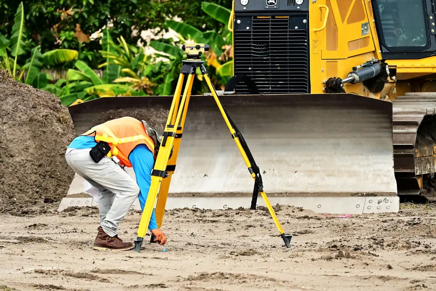 Geometra che fa un rilievo con la stazione totale in cantiere