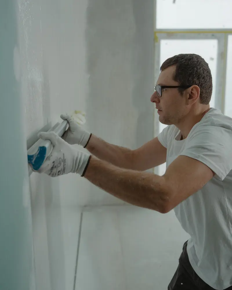 Muratore che stende lo stucco su una parete durante una ristrutturazione