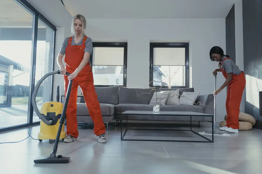 Due addette alle pulizie al lavoro in un soggiorno