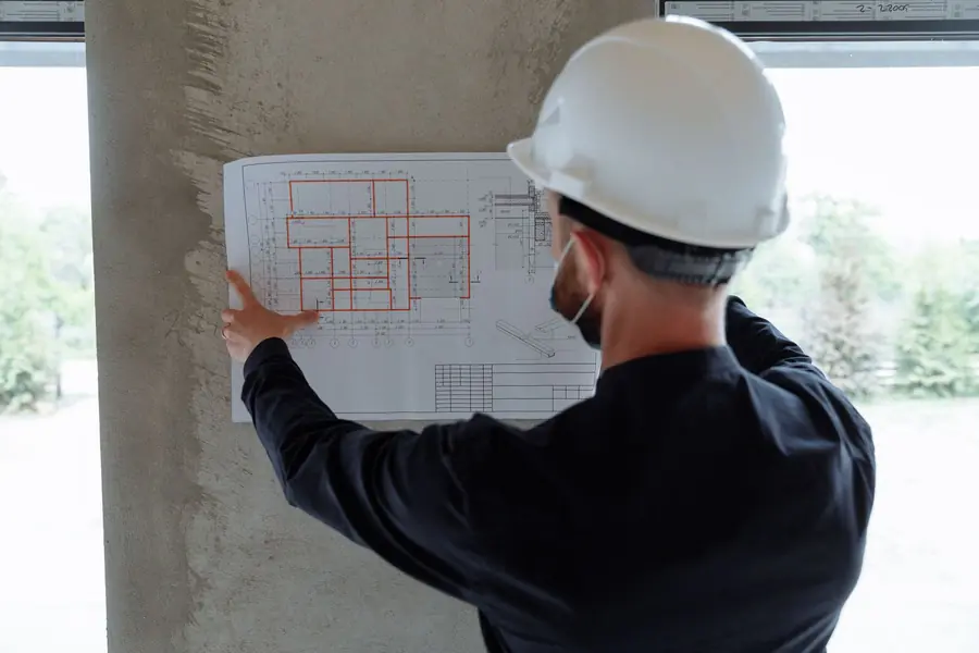 Ingegnere con il casco che controlla le piante del cantiere