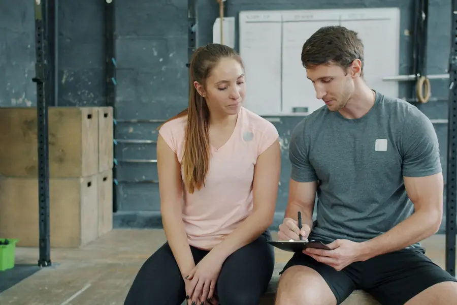 Personal trainer e cliente che guardano insieme il programma sul tablet