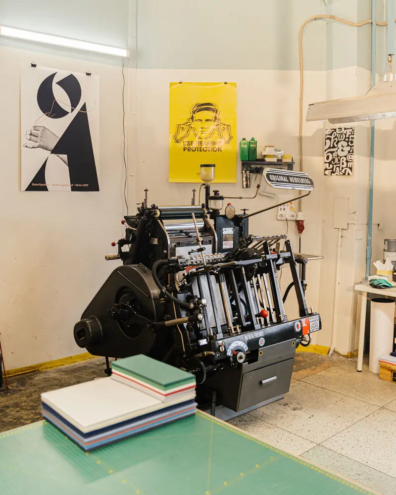 Laboratorio di stampa con una macchina tipografica e i manifesti alle pareti