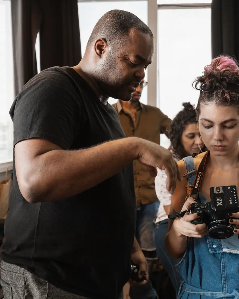 Istruttore che mostra a un'allieva come usare la fotocamera durante un workshop