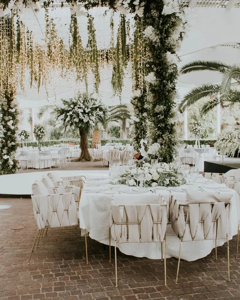 Sala di un matrimonio allestita con fiori bianchi, tavoli rotondi e piante